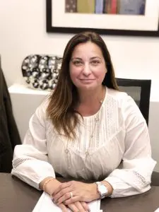 A woman sitting at a desk smiling at the camera.