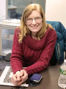 A woman in a red sweater smiling indoors.