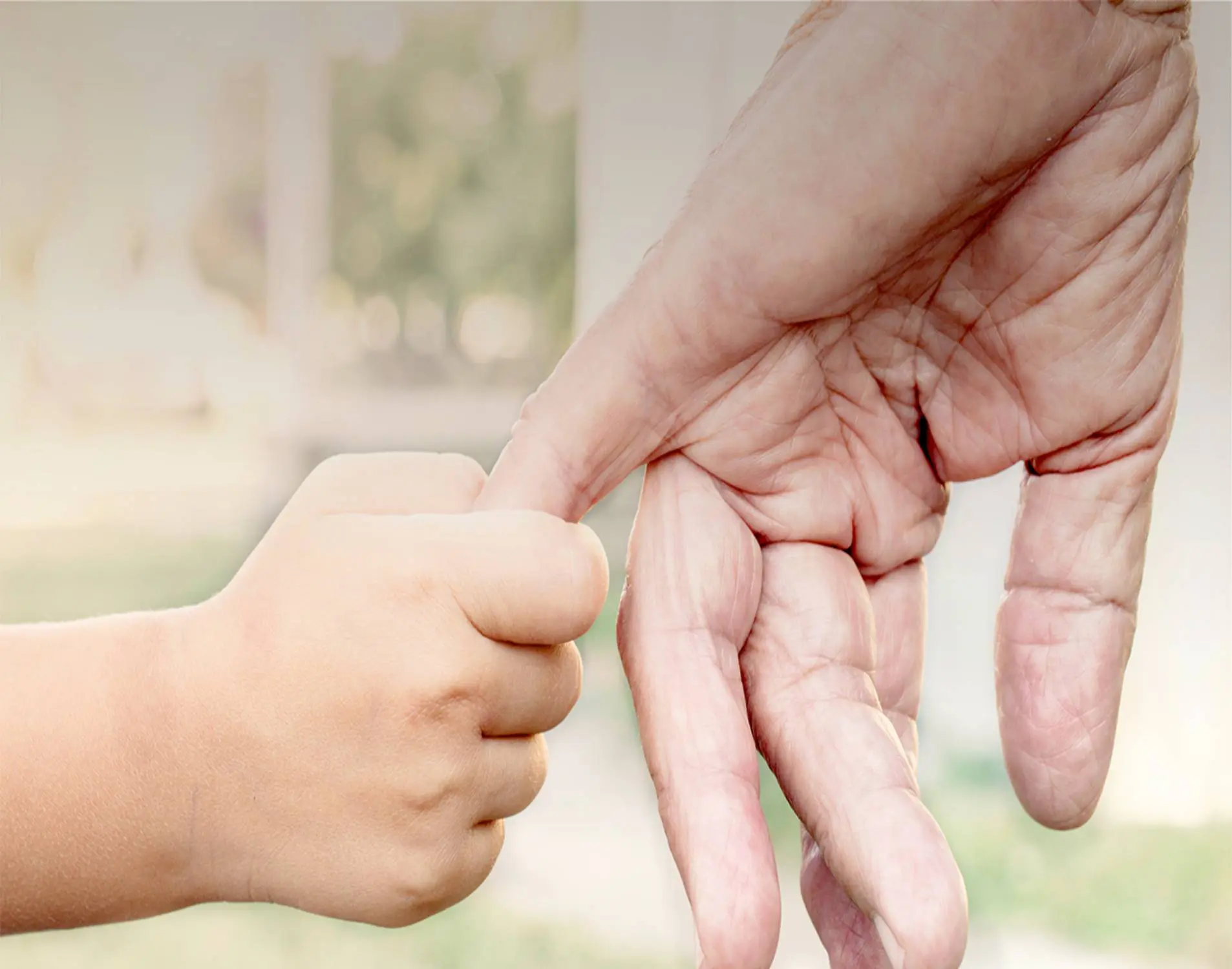 A child and an adult touching fists gently outdoors.